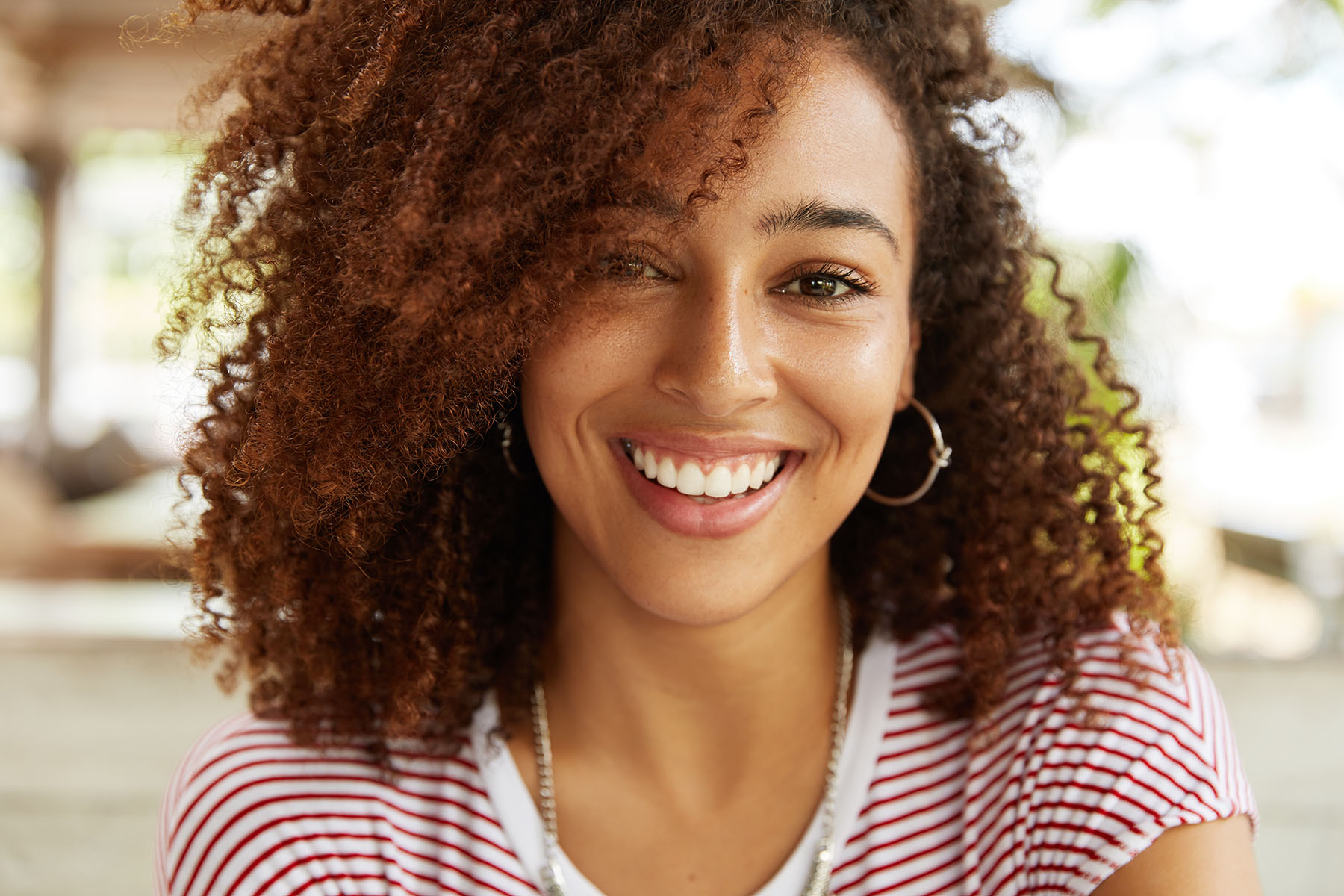 A woman with curly hair smiling into the camera.