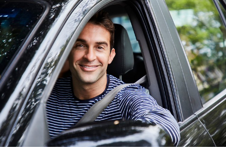Man smiling in car during commute.